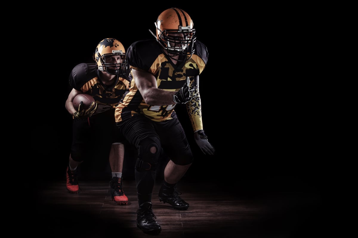 Leather sports ball and helmet on a dark background